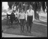 Two Alamada boys on a lawn with unidentified people sitting in rocking chairs behind them , Baja, 1920