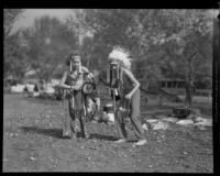 Boy Scouts in feather headdresses at a camping event in a park, circa 1935