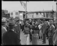 Women, probably participants in a Jack Kearns dance marathon, walk through a crowd towards a police patrol car, Los Angeles, probably 1934