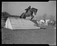 Miss Leon Wald jumping an obstacle with sloping sides at the Griffith Park Riding Academy, Los Angeles, 1932