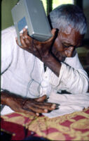 Doreswami listens to a recording of music made by A. A. Bake in 1938, Usilampatty (India), 1984