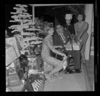 Veteran Allan Jarabin, with Shirley Jones, Dana Wynter and Lydia Lane, receives a present at Lydia Lane's annual Christmas party honoring military veterans, [Los Angeles?], 1963