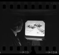 Detective looking at a projection of a diagram of a police shootout, Van Nuys, 1970
