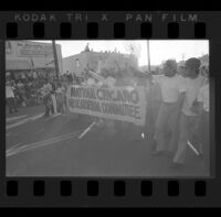 Marchers hold a sign for the National Chicano Moratorium Committee in a parade, Los Angeles, circa 1970