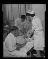 Attendent Clement, another male attendent, and Nurse Leah Lewis inject a patient with insulin to induce coma as part of a treatment for insanity at the Camarillo State Hospital, 1940