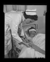 Nurse Leah Lewis administers a sugar solution to a patient undergoing insulin treatment for insanity at Camarillo State Hospital, 1940