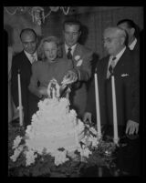Dick Powell and June Allyson cutting their wedding cake, Los Angeles, 1945