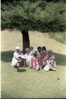 Toda men and children on a grassy bank with one man playing a bhugri, Udagamandalam (India), 1984