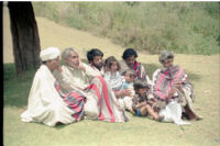 Toda men with children singing on a grassy bank with one man playing a bhugri, Udagamandalam (India), 1984