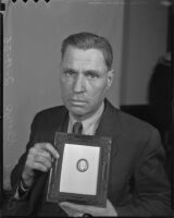 Charles Kemp holds a frame with a historic locket, Los Angeles, 1936