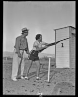 Mrs. Luke holds a gun with Carl Bradsher stands behind her, Palm Springs, 1936