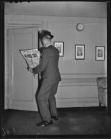 Timothy G. Turner, reporter for the Los Angeles Times, stands reading a newspaper, Los Angeles, 1939