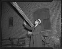 Detective Lieutenant Carl Shaemakn uses a flashlight to examine a bomb fuse, Los Angeles, 1935