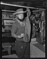 Chuckawalla Slim holding up a rattlesnake skin, Monrovia, 1935