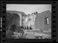 Visitors of Misson San Juan Capistrano admiring the ruins of a wall, San Juan Capistrano, 1936