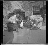 Two boys watch another boy attempt to make fire by friction, Los Angeles, about 1933