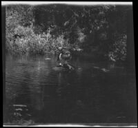 H. H. West Jr. climbs onto a raft after falling into a stream, Yosemite National Park, about 1929