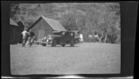 Two men next to car with wooden buildings in background at Twin Lakes, Bridgeport vicinity, 1929