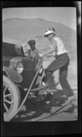 H. H. West Jr. holds a hose and pours water on a car, Indian Wells vicinity, 1929