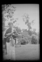 H. H. West Jr. poses holding his clarinet after participating in a parade, Alhambra, 1937