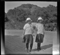 Frances and Elizabeth West in sailor-style dresses and hats standing at the entrance to Mountain Spring Ranch, Mount Baldy, 1914