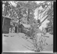 Agnes and Forrest Whitaker stand outside the Wells cabin in a snowy landscape, Big Bear, 1932