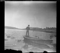 H. H. West, Jr. fishing in Big Bear Lake from a boat at the shore, Big Bear, 1932