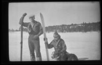 Neil Wells and H. H. West, Jr. holding skis as Neil Wells poses for a photograph and H. H. West, Jr. pets a dog, Big Bear, 1932