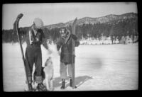 Neil Wells and H. H. West, Jr. play with a dog as they hold skis, Big Bear, 1932
