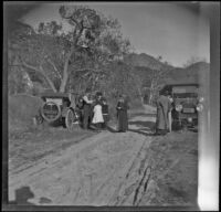 H. H. West's family and friends stand on a dirt road next to their parked cars, Sunland-Tujunga, 1912