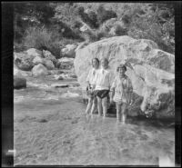 Elizabeth West, Frances West and Frances Cline pose for a photograph in front of a boulder in Big Tujunga Creek, Sunland-Tujunga vicinity, 1912