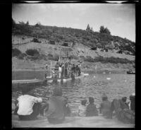 Boy scouts sit on a lakeshore and watch a showboat on Jackson Lake, Big Pines vicinity, 1933
