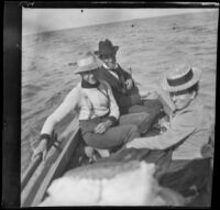 Nella West rides on a boat with two unidentified men, Santa Catalina Island vicinity, about 1901