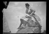 Woman sits on a rock with her hand over her face, Santa Catalina Island, 1903