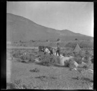 Glen Velzy, Wilf Cline and Chas Stavnow make camp among rocks and brush near the Cottonwood Creek power plant, Lone Pine vicinity, 1918