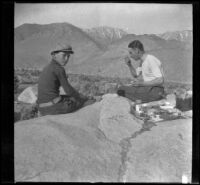 Wilfrid Cline and Glen Velzy eat supper on a rock off the side of the road, Lone Pine vicinity, 1918