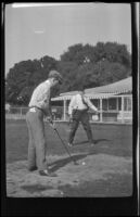 A man gets ready to hit a golf ball as Jim Scullin watches, Monterey vicinity, about 1920
