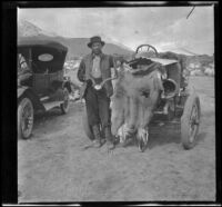 H. H. West stands by a car and poses with deer skin and antlers, Independence vicinity, 1916