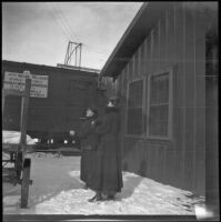A couple women stand outside the train station, Flagstaff, winter 1914