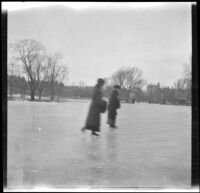 Two women ice skate on a frozen pond in the Public Garden, Boston, 1914