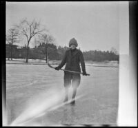 Boy ice skates and holds a hockey stick on a frozen pond, Boston, 1914