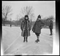 Two children ice skate on a frozen pond, Boston, 1914