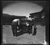 Glen Velzy fixing a headlight on H. H. West's Buick, Lancaster vicinity, 1915
