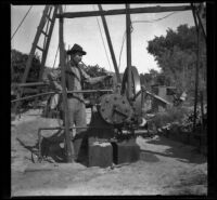 Will Mead stands by the gas engine at the well, Glendale, 1898
