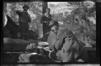 H. H. West cooking trout in camp near near Gardner Creek, about 1919
