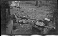 H. H. West cooking trout in camp near near Gardner Creek, about 1919