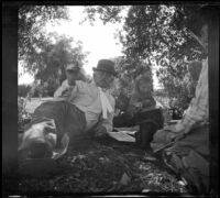 H. H. Cooper reclines while Elizabeth and Frances West, Wilhelmina West, and Mary West sit around a picnic blanket, Glendora, about 1910