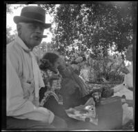 H. H. Cooper smokes a cigar while Elizabeth, Frances, and Wilhelmina West sit around a picnic blanket, Glendora, about 1910