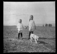 Frances and Elizabeth West hold hands while a dog walks in front of them, Claremont, about 1910
