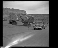 Mertie West standing beside a sign painted on a rock advertising the Cliff Dwellers Inn, Marble Canyon, 1942